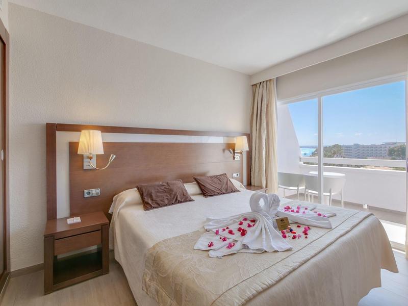 Chambre double lumineuse avec balcon, décorée avec des serviettes et des pétales de rose.