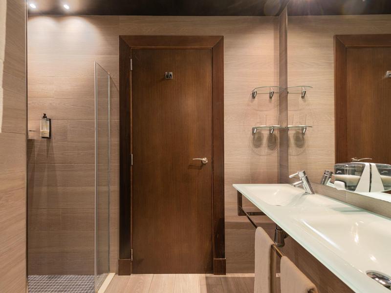 Salle de bain moderne avec détails en bois, double vasque et grand miroir.