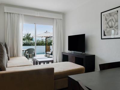 Modern living room with sofa, TV, balcony, and sea view