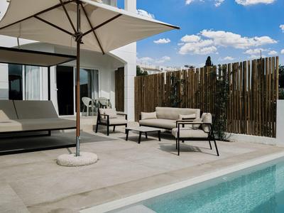 Moderner Außenbereich mit Pool, hellen Fliesen, Sonnenschirm und bequemen Lounge-Möbeln.