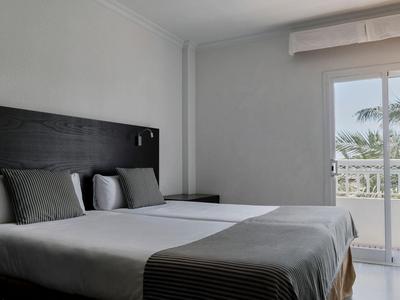 Modernes Schlafzimmer mit zwei Einzelbetten und Zugang zu einem Balkon mit Meerblick.