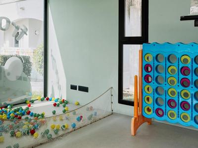 Innenraum mit großem blauen Spielgerät "Vier gewinnt" und Glaskugelbahn mit bunten Kugeln.