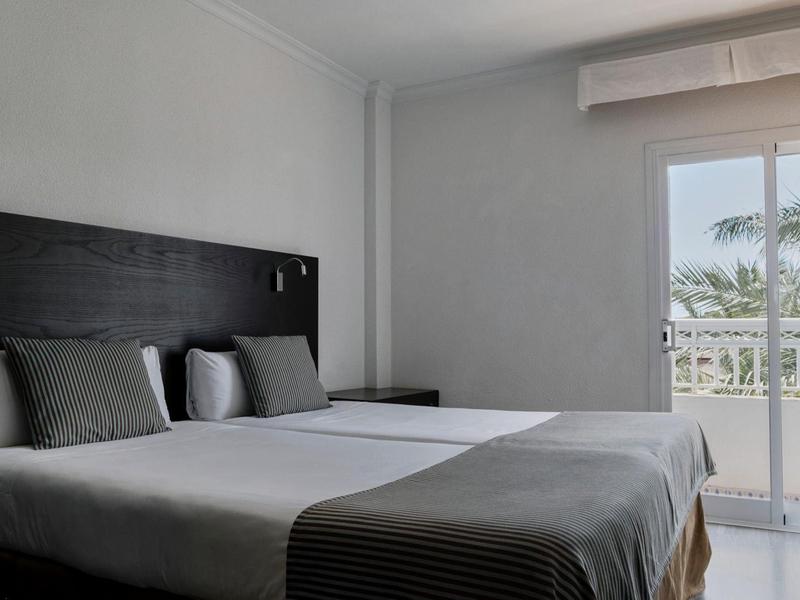 Modernes Schlafzimmer mit zwei Einzelbetten und Zugang zu einem Balkon mit Meerblick.