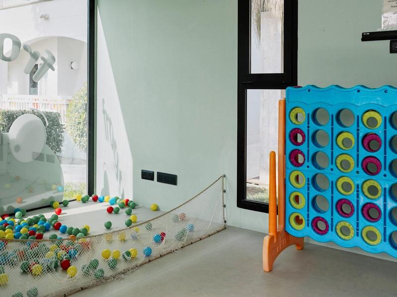 Innenraum mit großem blauen Spielgerät "Vier gewinnt" und Glaskugelbahn mit bunten Kugeln.