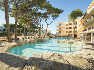 Piscine d'hôtel avec transats et arbres environnants sous un ciel clair