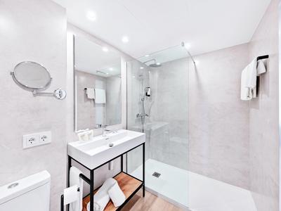 Salle de bain moderne avec grande douche à l'italienne, lavabo et toilette dans des tons clairs.