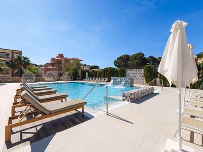 Piscine d'hôtel moderne avec chaises longues et parasols sous un ciel dégagé.