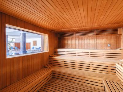 Intérieur d'un sauna avec des bancs en bois à plusieurs niveaux et une grande fenêtre.