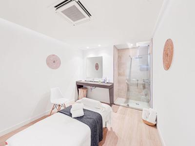 Salle de bien-être lumineuse avec table de massage et douche dans un style moderne.