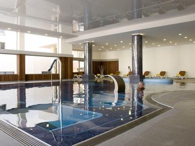Piscine intérieure moderne avec carreaux lisses et grandes fenêtres dans un hôtel.