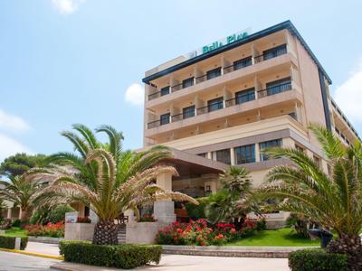 Bâtiment d'hôtel à plusieurs étages avec des palmiers et un jardin soigné devant