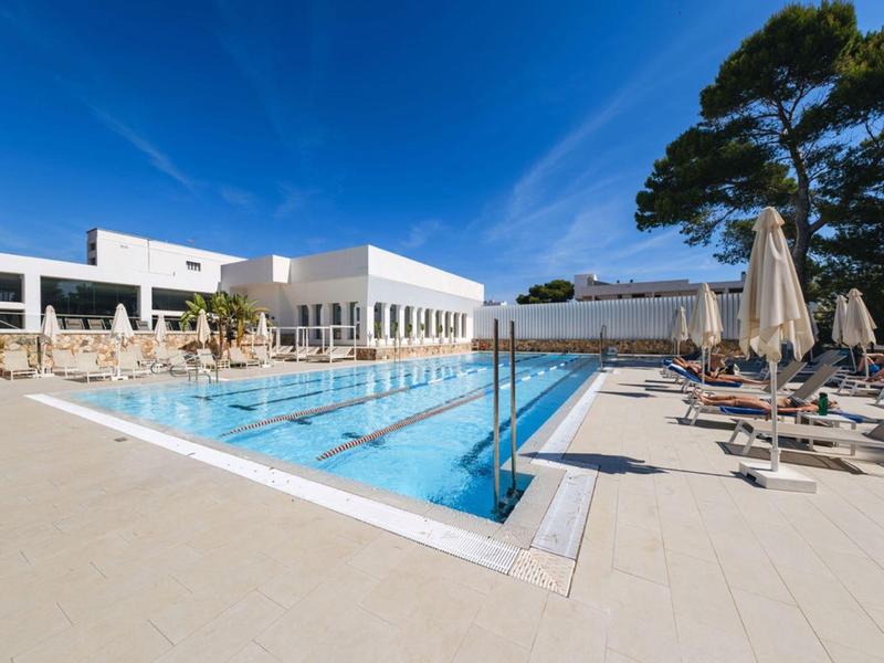 Piscine d'hôtel moderne avec chaises longues et parasols sous un ciel bleu