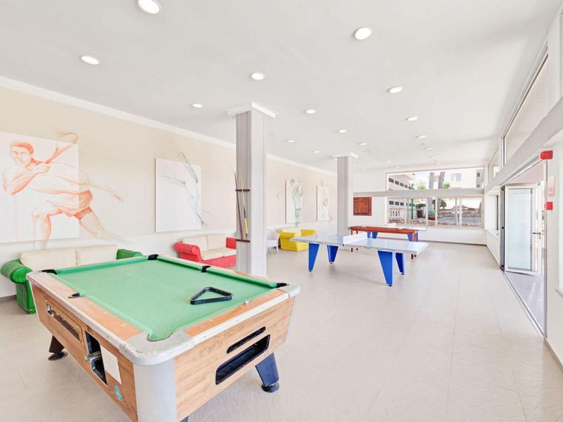 Salle de jeux lumineuse avec table de billard et table de air hockey au design moderne.