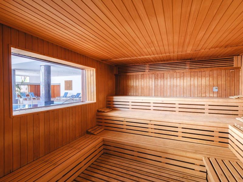 Intérieur d'un sauna avec des bancs en bois à plusieurs niveaux et une grande fenêtre.