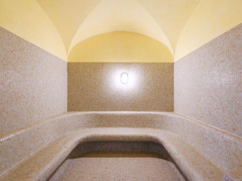 Sauna lumineuse avec bancs en pierre claire et plafond voûté.