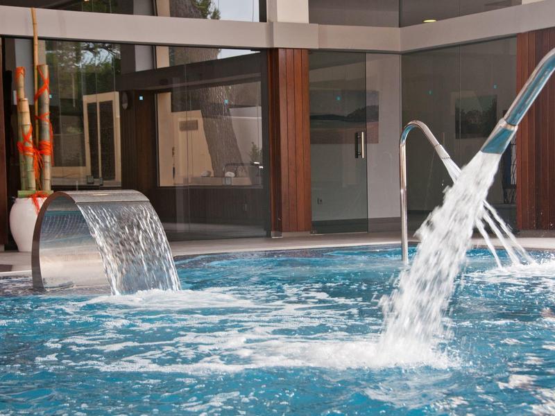 Piscine intérieure avec jeux d'eau et décor moderne dans un hôtel.