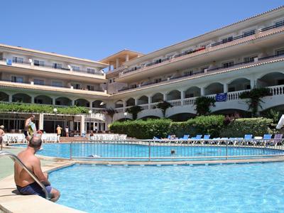 Grande hotel con piscina all'aperto e lettini sotto il sole.