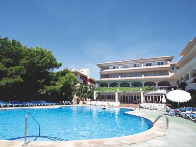 Grande piscina davanti a un edificio di hotel su più piani sotto un cielo azzurro.
