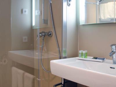 Arredamento bagno moderno con doccia, lavabo e asciugamani in una camera d'albergo.