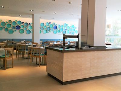 Area pranzo moderna dell'hotel con decorazioni murali blu e mobili color legno.