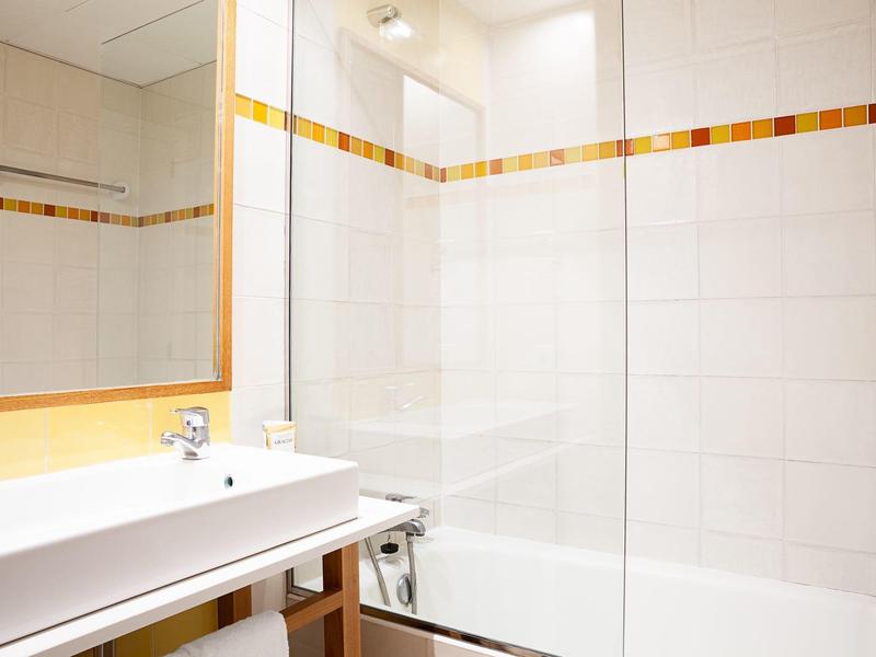 Bagno luminoso con vasca da bagno bianca, lavabo e accenti arancioni sulle piastrelle.