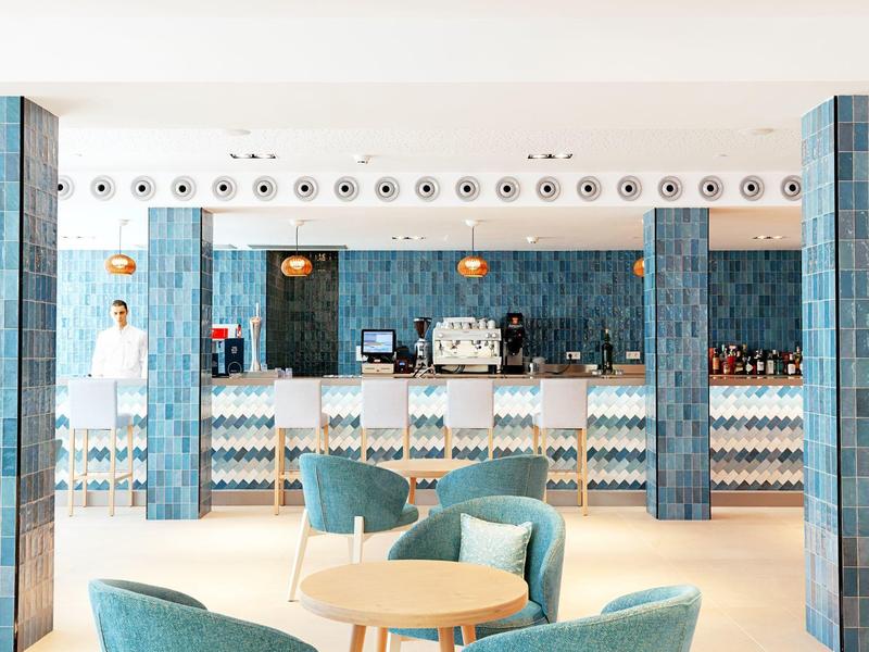 Lounge luminosa con motivo di piastrelle blu-turchese, banco bar e posti a sedere accoglienti.