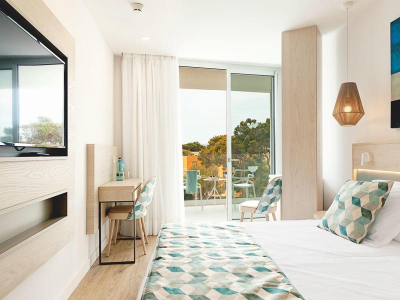 Camera d'hotel luminosa con mobili moderni, grande finestra e balcone con vista.