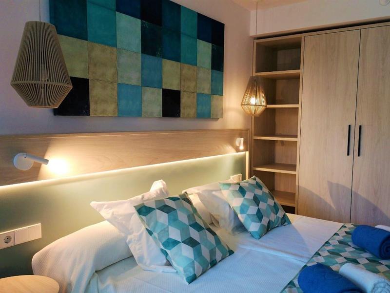 Camera d'hotel moderna con letto matrimoniale, cuscini decorativi e quadro blu.