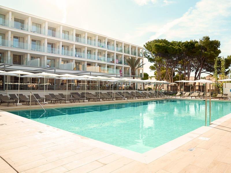 Complesso alberghiero moderno con piscina e ombrelloni in ambiente soleggiato.