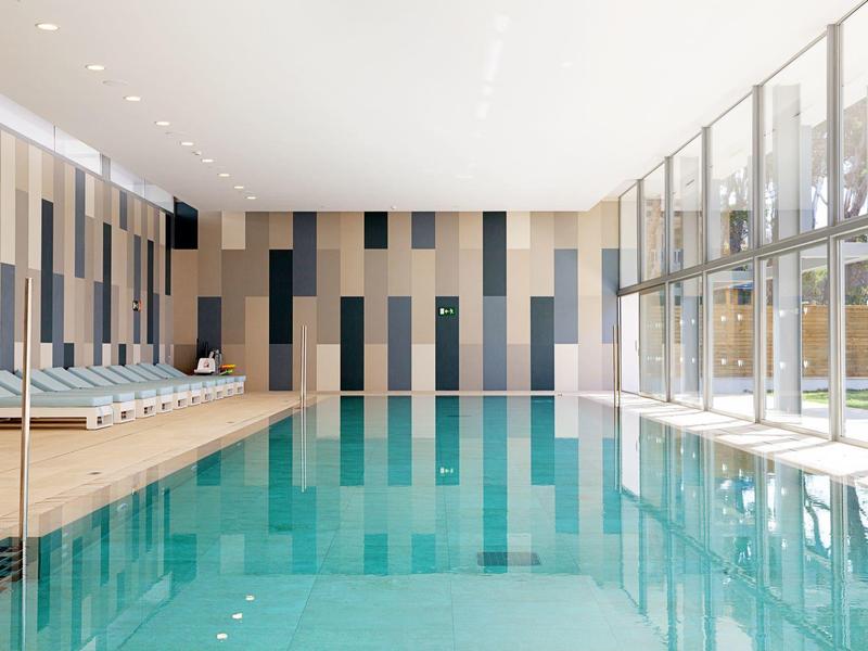 Piscina interna moderna con grande finestra e lettini accanto alla piscina