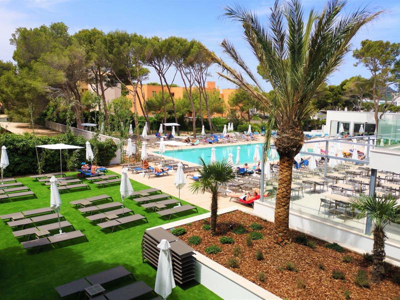 Piscina moderna dell'hotel con lettini, ombrelloni e palme in un ambiente soleggiato