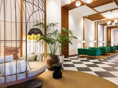 Area reception moderna con altalena, divano verde e pavimento a scacchiera