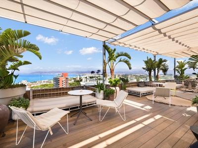 Lounge terrazza con pavimento in legno, mobili bianchi e vista mare in giornata soleggiata