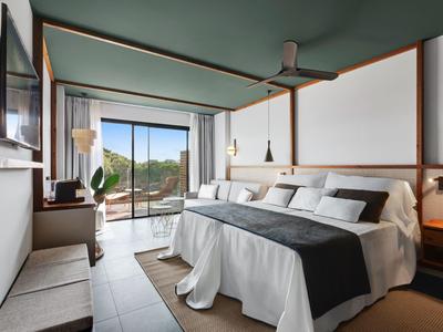 Camera d'hotel moderna con letto matrimoniale, balcone e vista sulla natura