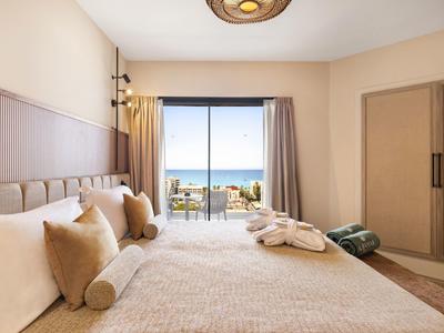 Camera luminosa con letto grande, balcone con vista mare e tonalità neutre.