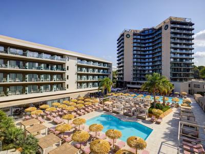 Complesso alberghiero moderno con grande piscina e molti ombrelloni in una giornata di sole