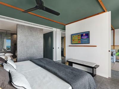 Camera d'hotel moderna con letto matrimoniale, ventilatore a soffitto, TV e area bagno aperta.