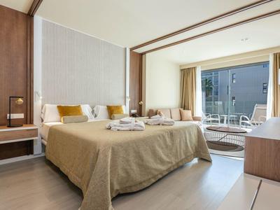 Camera d'hotel moderna con letto grande, scrivania e balcone con vista sulla città.