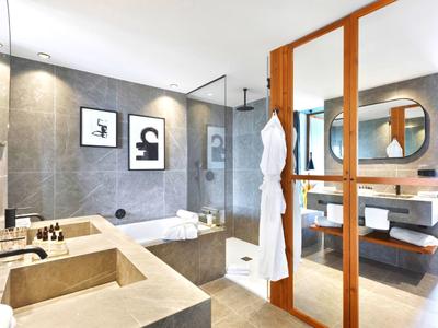 Bagno moderno con doppi lavandini, ampia doccia e dettagli in legno chiaro.