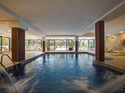 Area piscina interna in hotel con giochi d'acqua e lettini