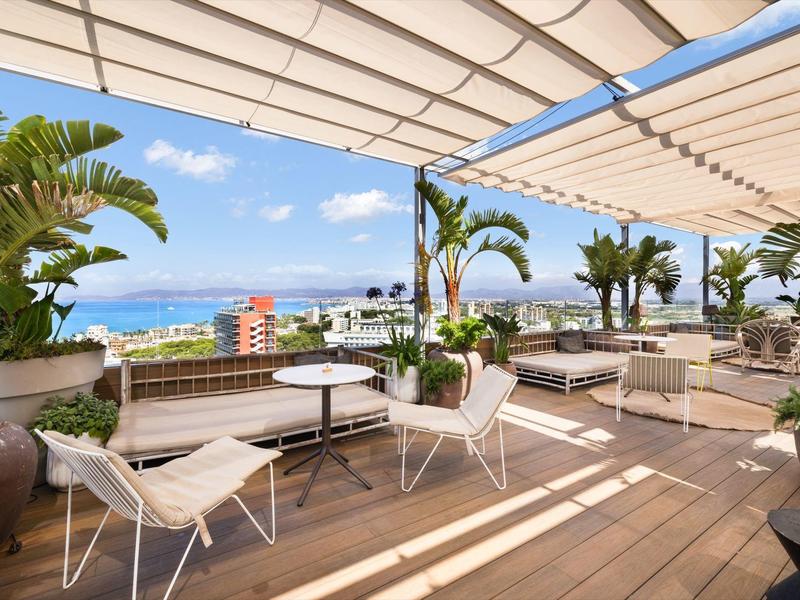 Lounge terrazza con pavimento in legno, mobili bianchi e vista mare in giornata soleggiata