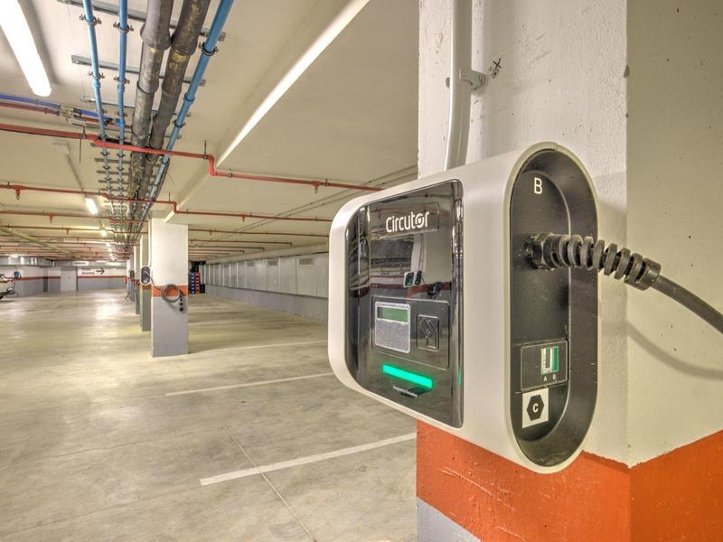 Stazione di ricarica per auto elettriche in un parcheggio con posti auto delimitati.