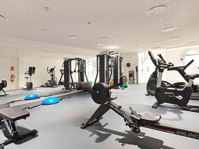 Palestra luminosa con varie attrezzature per allenamento e specchi alle pareti