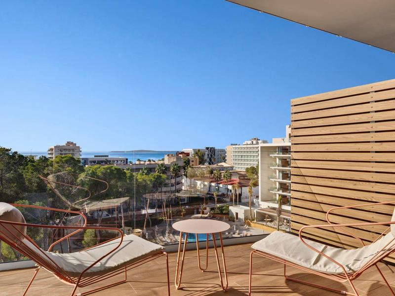 Balcone con due sdraio e piccolo tavolo, vista sulla città e sul mare sullo sfondo.