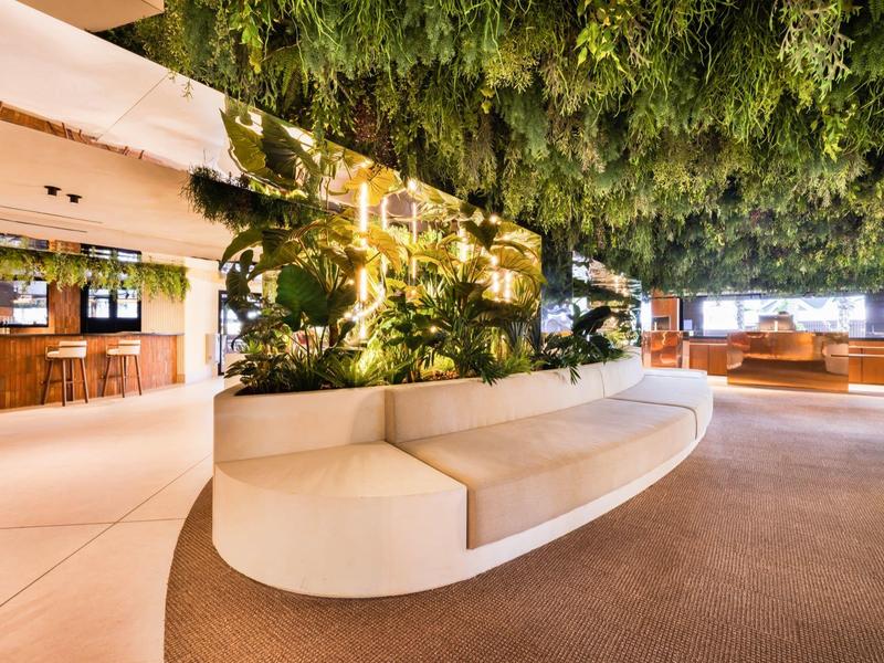 Area lounge dell'hotel moderna con panca bianca curva e molta vegetazione.