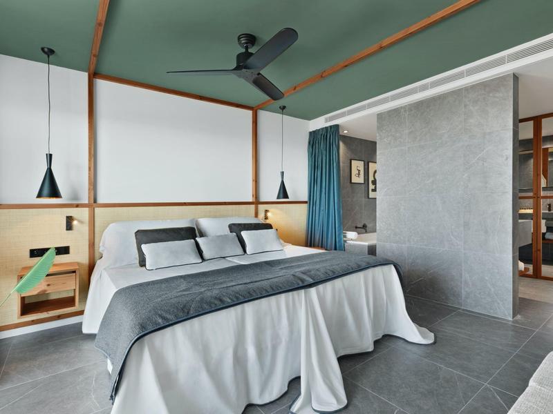 Camera d'hotel moderna con letto grande, biancheria grigia e bianca e design minimalista.