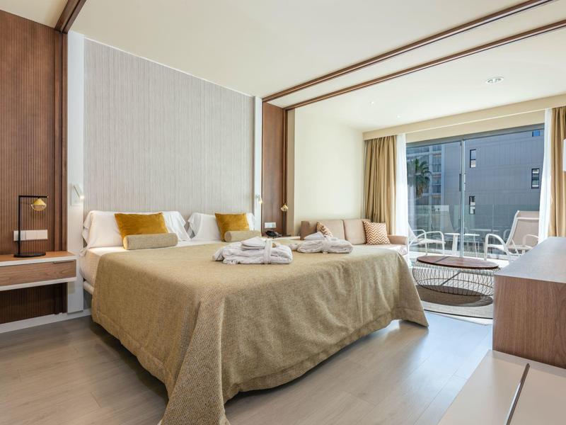 Camera d'hotel moderna con letto grande, scrivania e balcone con vista sulla città.