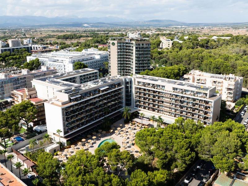 Grande hotel con più edifici circondati da alberi e panorama urbano sullo sfondo.