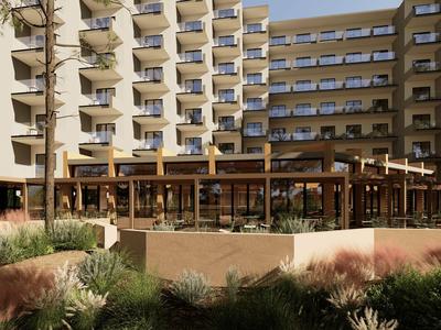 Moderner Hotelkomplex mit Balkonen und begrüntem Innenhof bei Sonnenlicht.