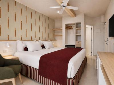 Modernes Hotelzimmer mit großem Bett, grünem Sessel, Flachbildschirm und Schreibtisch.